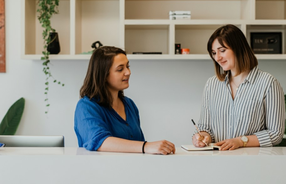 Two women standing at a reception desk